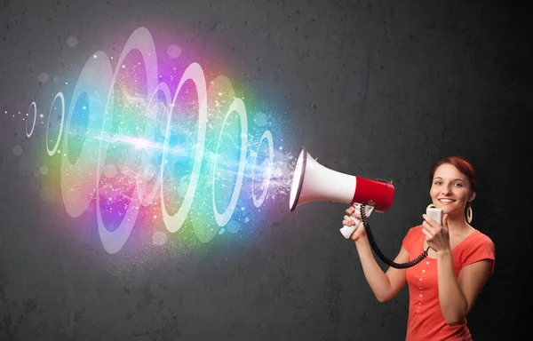 Young girl yells into a loudspeaker and colorful energy beam com — Stock Photo, Image