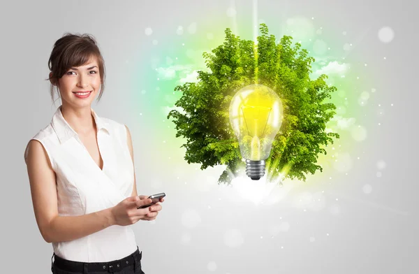 Young girl presenting idea light bulb with green tree — Stock Photo, Image