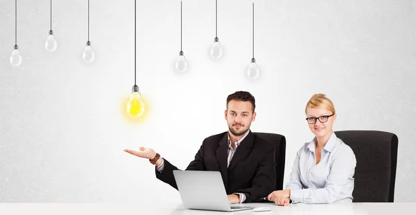 Obchodní muž a žena, sedící u stolu s myšlenkou žárovky — Stock fotografie