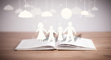 Ailenin karton figürleri açık bir kitabın üzerinde.