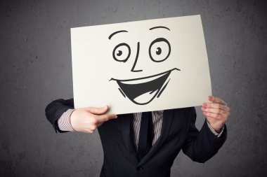 empresario sosteniendo una cartulina con cara sonriente en él en frente 