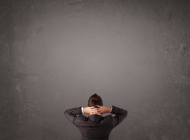 Boş bir duvarın önünde duran bir iş adamı.