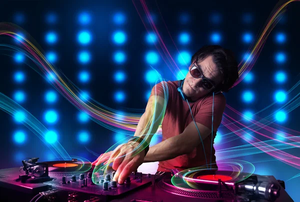 Junger DJ mischt Platten mit bunten Lichtern — Stockfoto