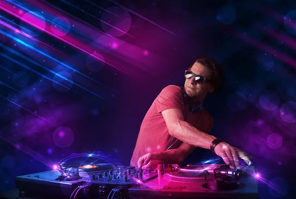 Young DJ playing on turntables with color light effects — Stock Photo, Image