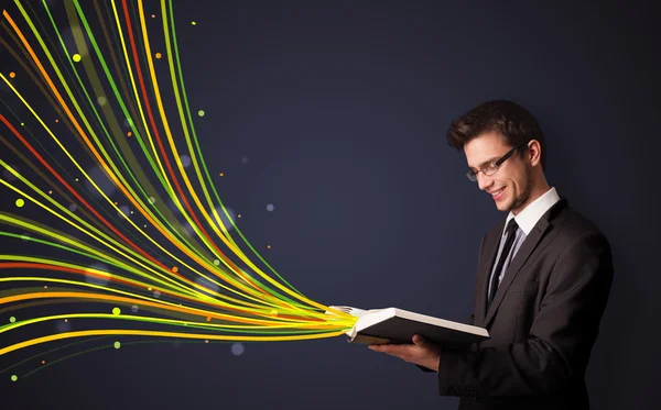 Hombre guapo leyendo un libro mientras líneas coloridas están saliendo —  Fotos de Stock