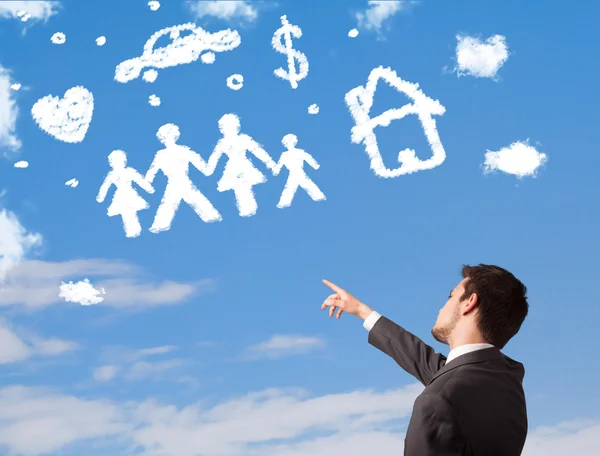 Businessman daydreaming with family and household clouds — Stock Photo, Image