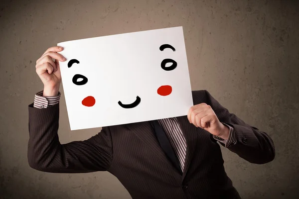 Επιχειρηματίας κρατώντας ένα χαρτόνι με ένα χαμογελαστό πρόσωπο σε αυτό — Φωτογραφία Αρχείου