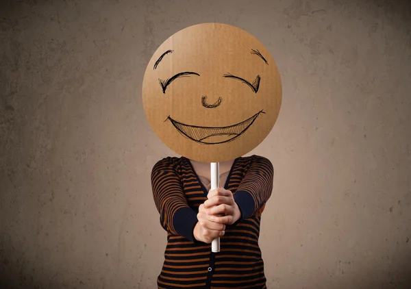 Mujer joven sosteniendo una carita sonriente — Foto de Stock