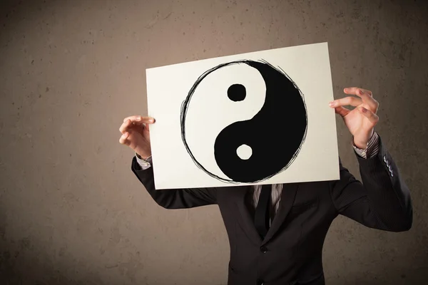 Empresario sosteniendo un papel con un yin-yang en frente de hi — Foto de Stock