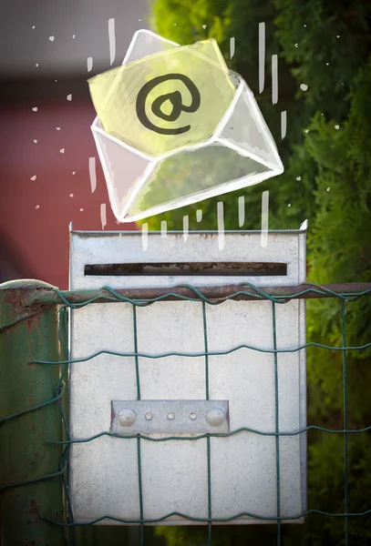 Envelope with email sign dropping into mailbox — Stock Photo, Image