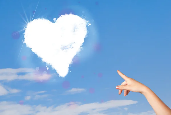 Hand pointing at white heart cloud on blue sky — Stock Photo, Image