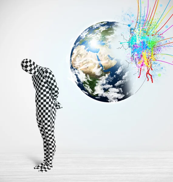 Funny man in body suit looking at colorful splatter earth — Stock Photo, Image