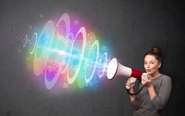 Young girl yells into a loudspeaker and colorful energy beam com — Stock Photo, Image