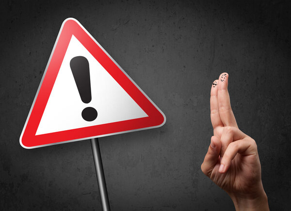 Счастливые улыбающиеся пальцы глядя на треугольник предупреждающий знак с excla
