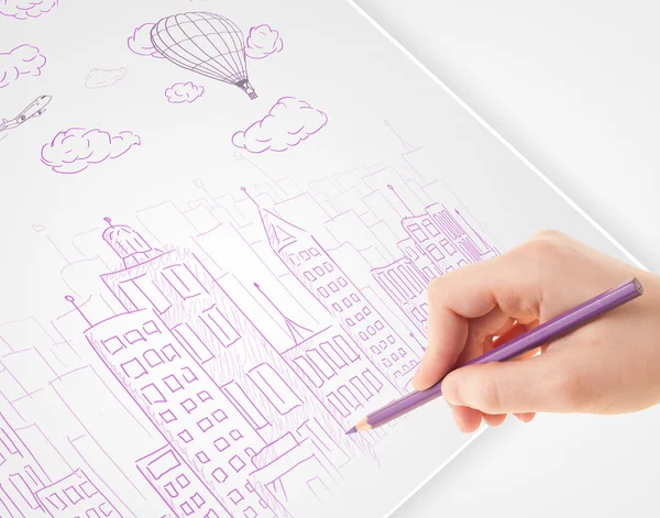 A person drawing sketch of a city with balloons and clouds on a — Stock Photo, Image