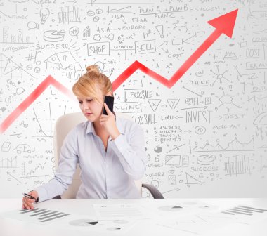 Piyasa diyagramlarıyla masada oturan iş kadını. 