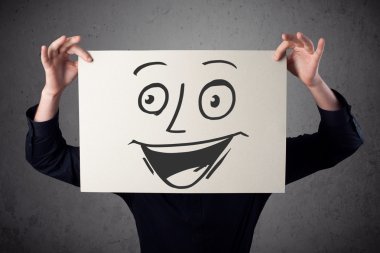 empresario sosteniendo una cartulina con cara sonriente en él en frente 
