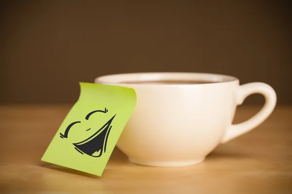 Nota post-it con la cara sonriente pegada en la taza — Foto de Stock