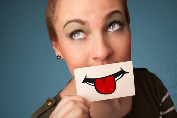 Happy pretty woman holding card with funny smiley — Stock Photo, Image