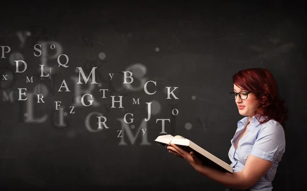 Junge Frau liest ein Buch mit Buchstaben des Alphabets — Stockfoto