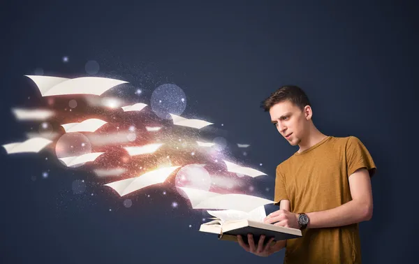 Ung kille läser en bok med flygande lakan kommer från bo — Stockfoto