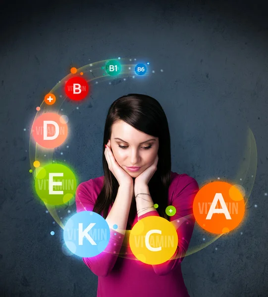 Young woman thinking with vitamins circulation around her head — Stock Photo, Image