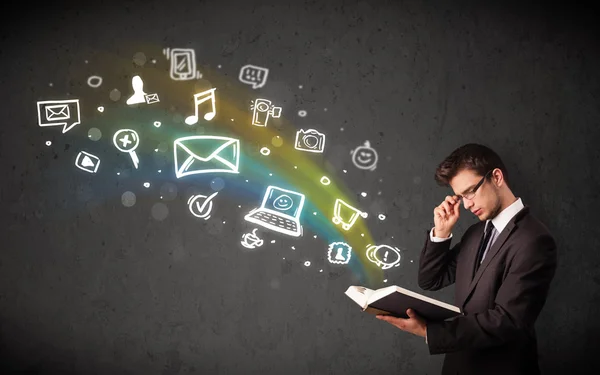 Joven hombre de negocios leyendo un libro con iconos multimedia — Foto de Stock