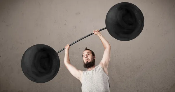 Funny skinny guy lifting weights — Stock Photo, Image