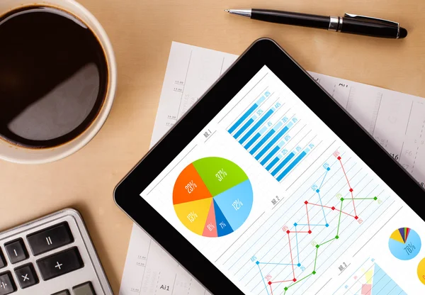 Tabletpc toont grafieken op het scherm met een kopje koffie op een bureau — Stockfoto