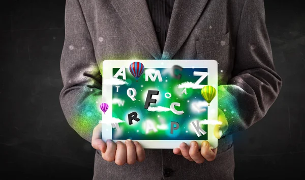Joven mostrando tableta con letras abstractas y cielo — Foto de Stock