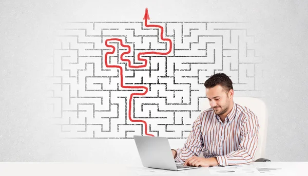 Business man at desk with labyrinth and arrow — Stock Photo, Image