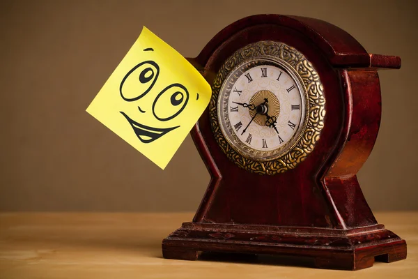 Post-it nota con la cara sonriente pegado en el reloj — Foto de Stock