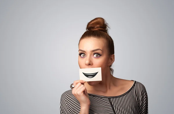 Happy pretty woman holding card with funny smiley — Stock Photo, Image