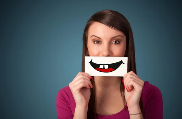 Happy pretty woman holding card with funny smiley — Stock Photo, Image