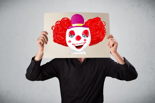 Geschäftsmann hält einen Karton mit einem Clown davor — Stockfoto