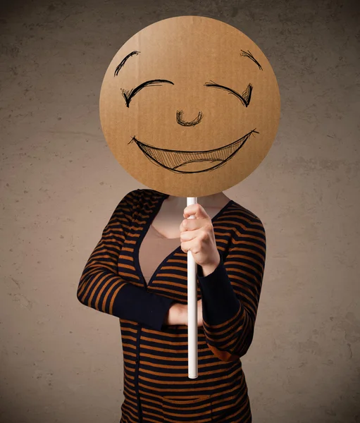 Young woman holding a smiley face board — Stock Photo, Image