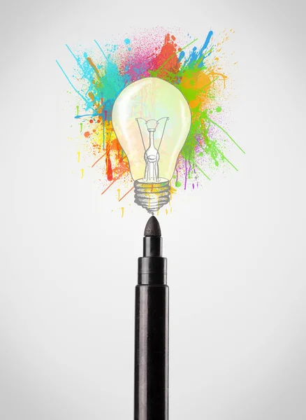 Фелтовая ручка крупным планом с цветными брызгами краски и лампочкой — стоковое фото