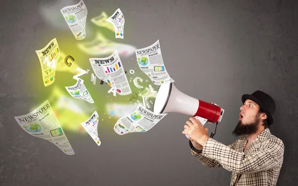 Guy yelling into loudspeaker and newspapers fly out — Stock Photo, Image