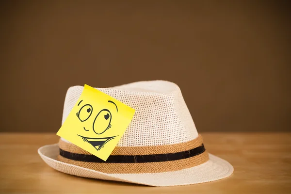 Nota post-it con la cara sonriente pegada en el sombrero — Foto de Stock