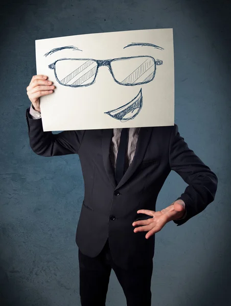 Empresario sosteniendo un papel con la cara sonriente delante de su hea — Foto de Stock