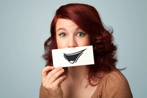 Happy cute girl holding paper with funny smiley drawing — Stock Photo, Image