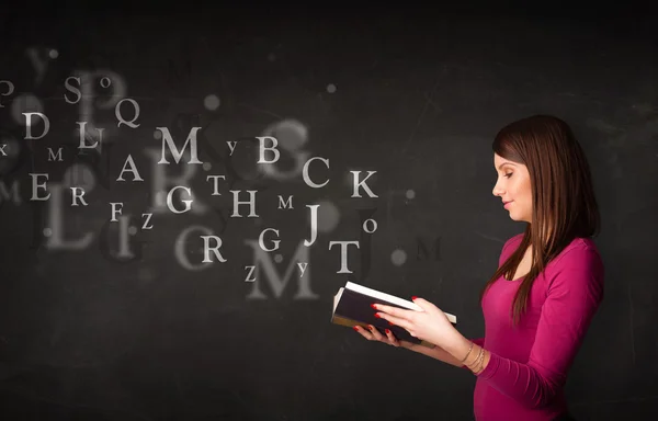 Giovane signora che legge un libro con lettere alfabetiche — Foto Stock