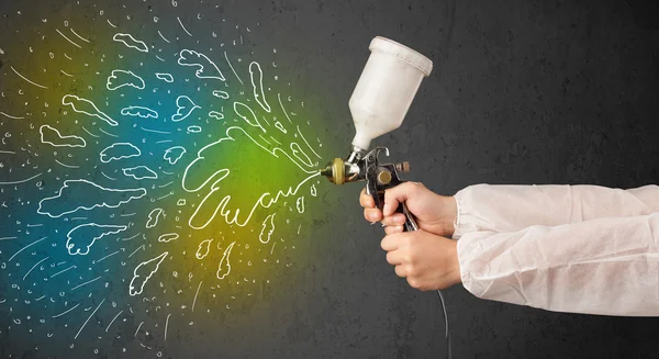 Worker with airbrush gun paints colorful lines and splashes — Stock Photo, Image