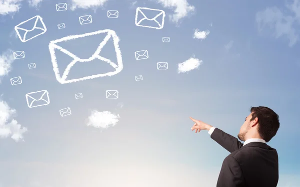 Hombre de negocios mirando el símbolo de correo nubes en el cielo azul — Foto de Stock