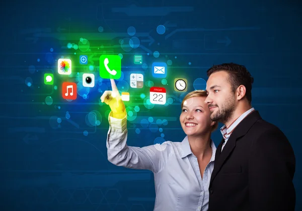 Jeune couple d'affaires appuyant sur les icônes colorées application mobile avec bo — Photo