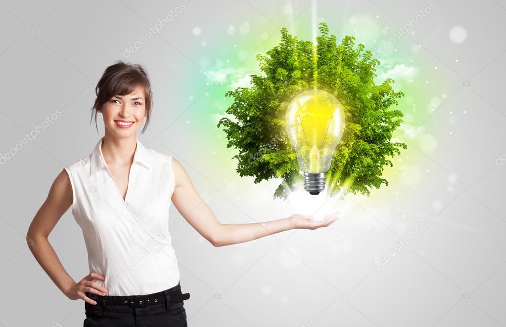 Young girl presenting idea light bulb with green tree 