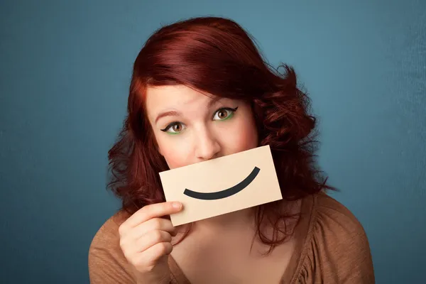 Feliz bonita mujer sosteniendo tarjeta con divertido smiley — Foto de Stock