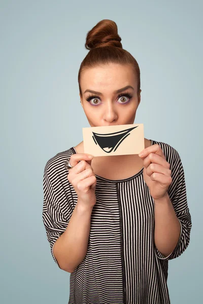 Happy cute girl holding paper with funny smiley drawing — Stock Photo, Image