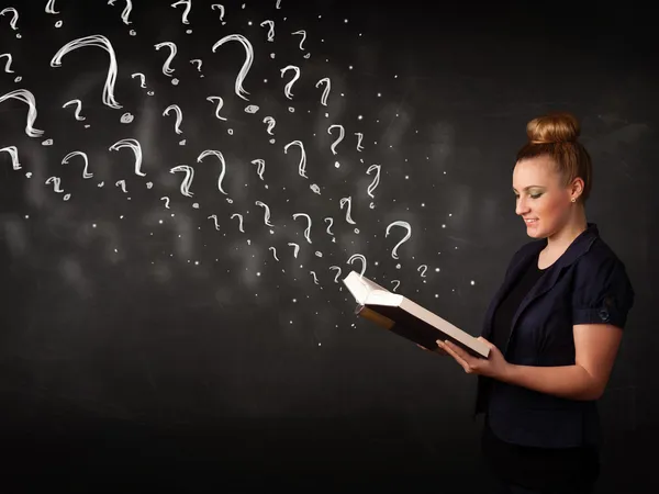 Pretty woman reading a book with question marks coming out from — Stock Photo, Image