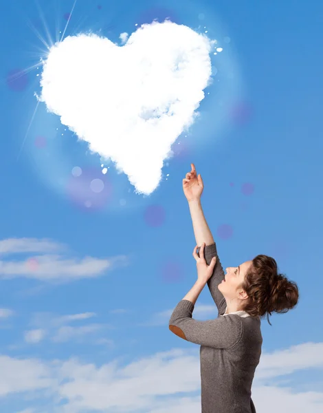 Мила дівчина дивиться на хмару білого серця на блакитному небі — стокове фото